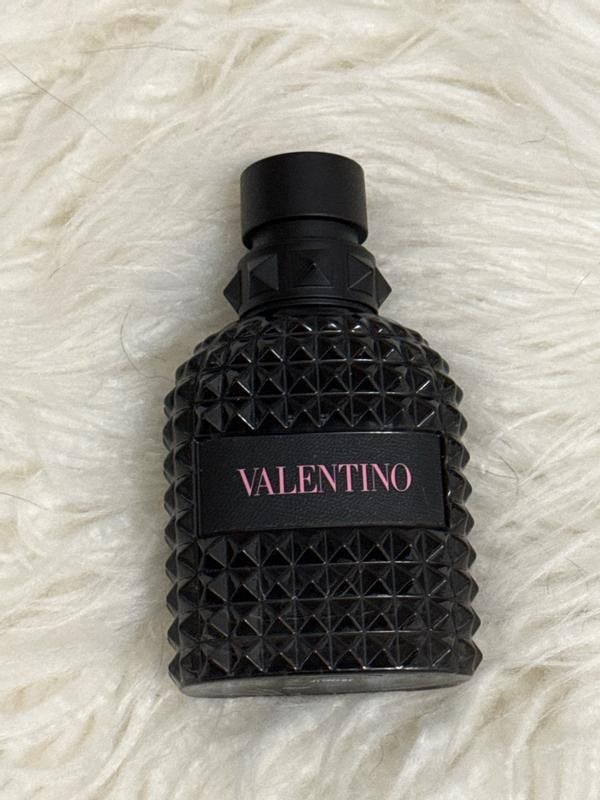 Flacon de parfum homme noir pose sur un plaid clair