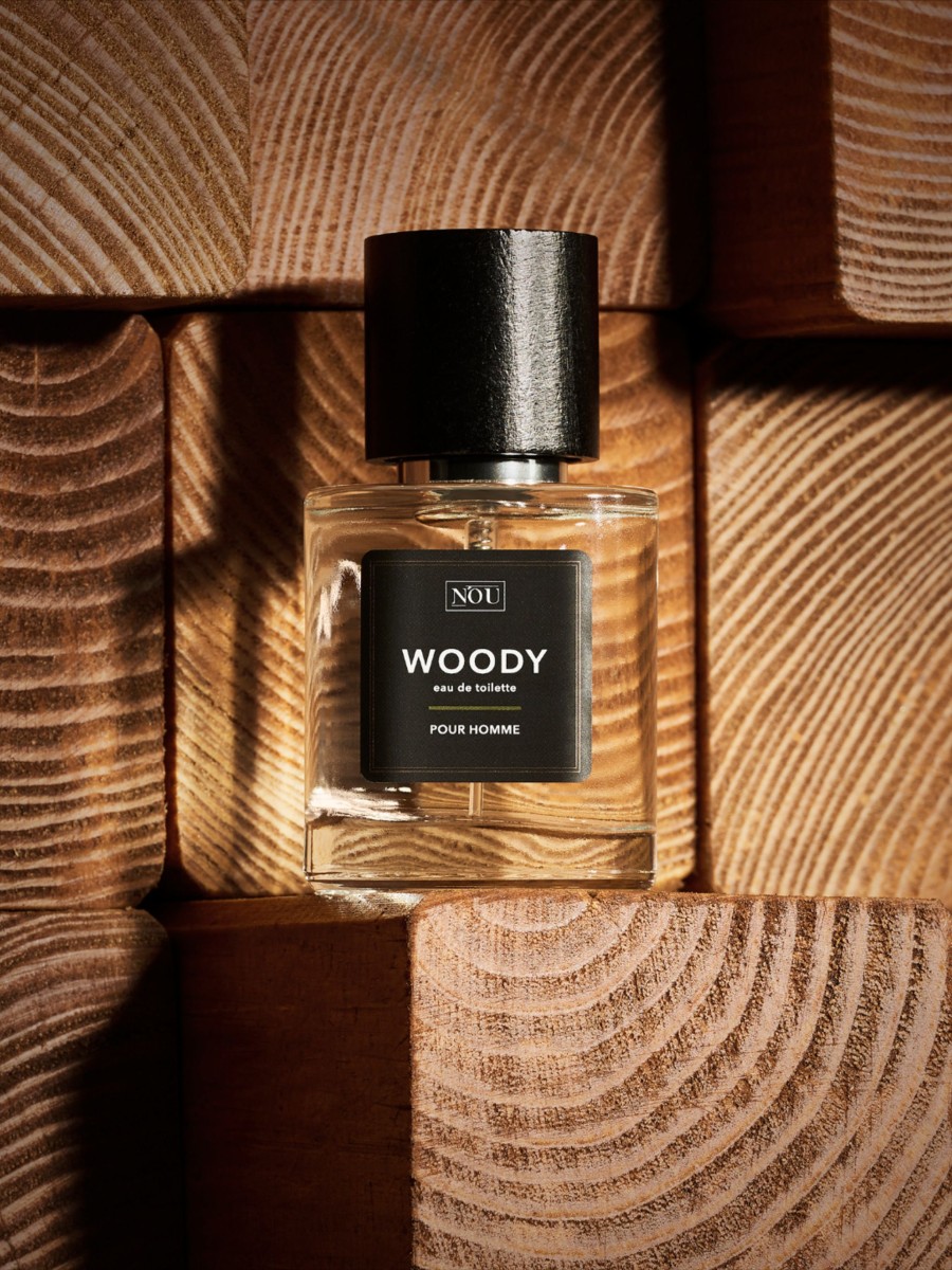 Eau de toilette homme aux notes boisees posee sur des rondins de bois